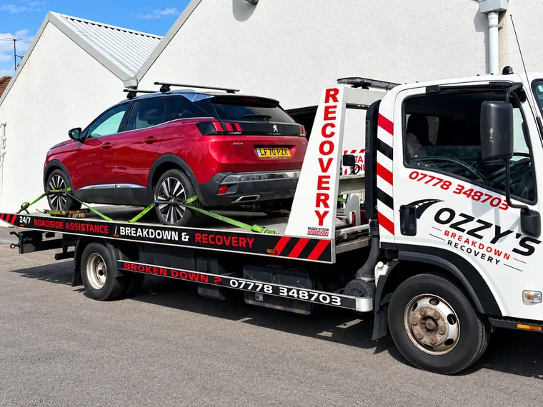 Ozzy’s Breakdown Recovery truck carrying a red Peugeot SUV